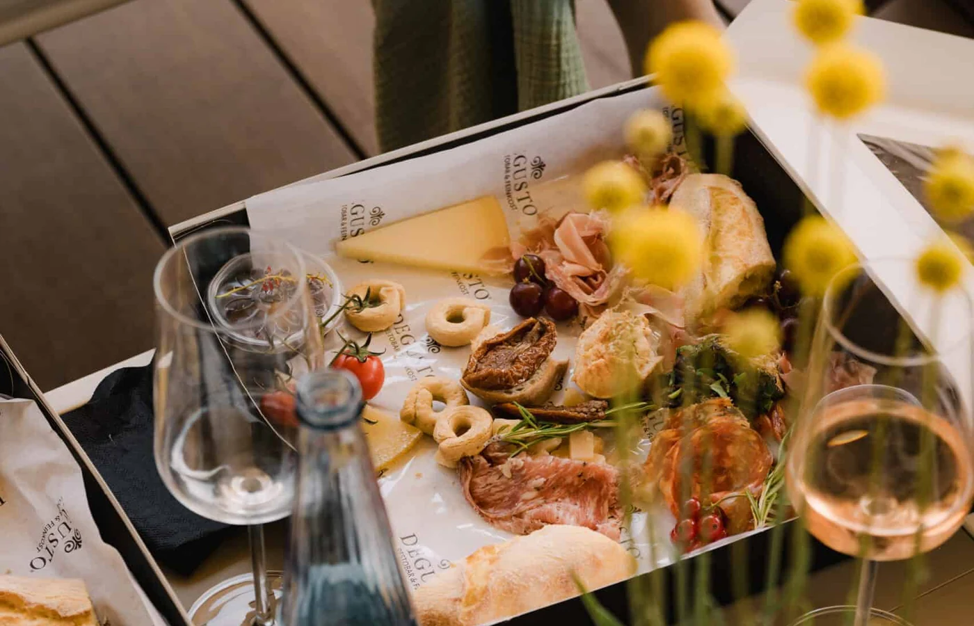 Zwei geöffnete Cateringboxen auf DEGUSTO-Papier, gefüllt mit Käse, Schinken, Taralli und Brot