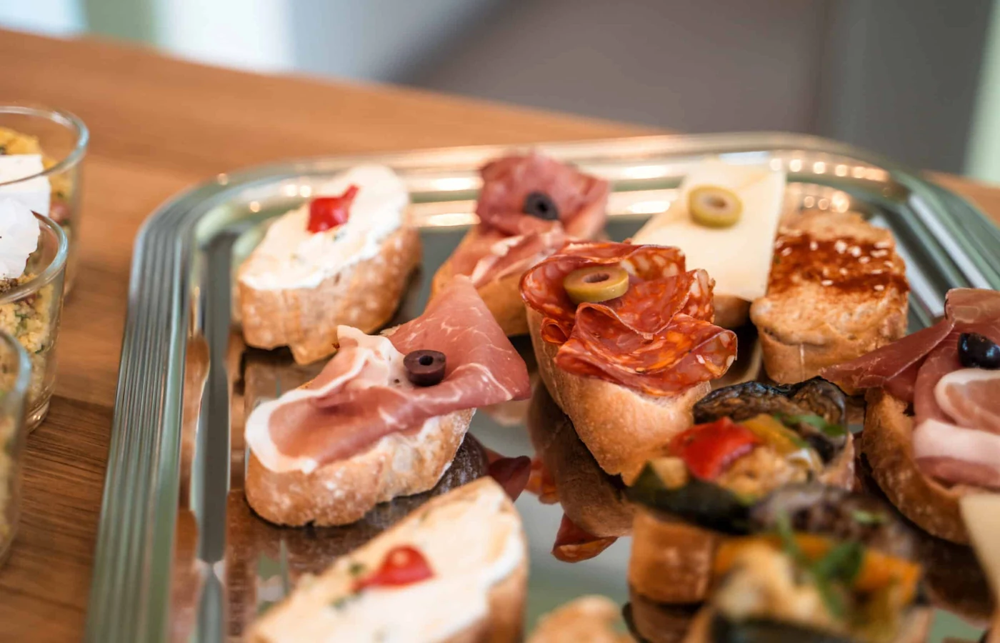 Belegte Canapés mit Parmaschinken, Salami, Käse und Oliven auf einer Platte