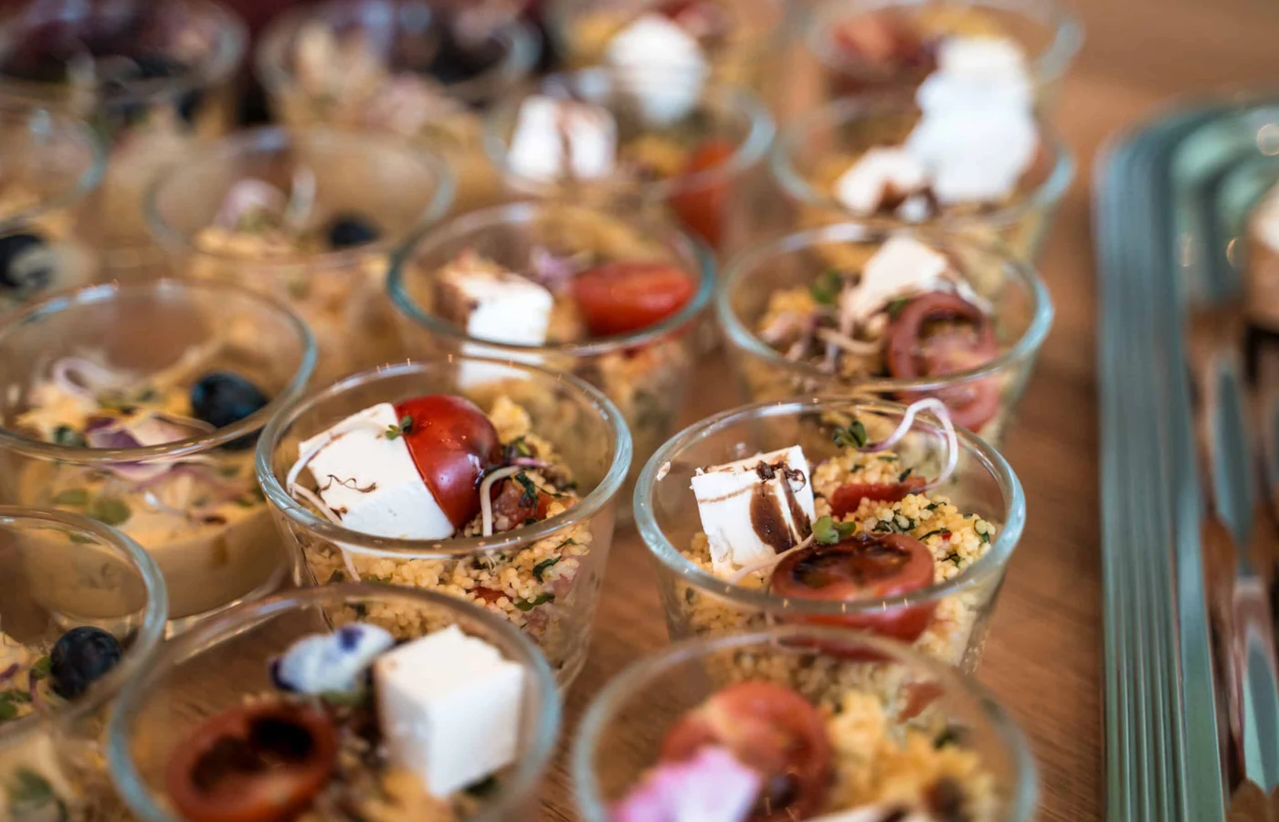 Gläser mit Couscous-Salat, Feta und Tomate, dicht an dicht auf dem Tisch
