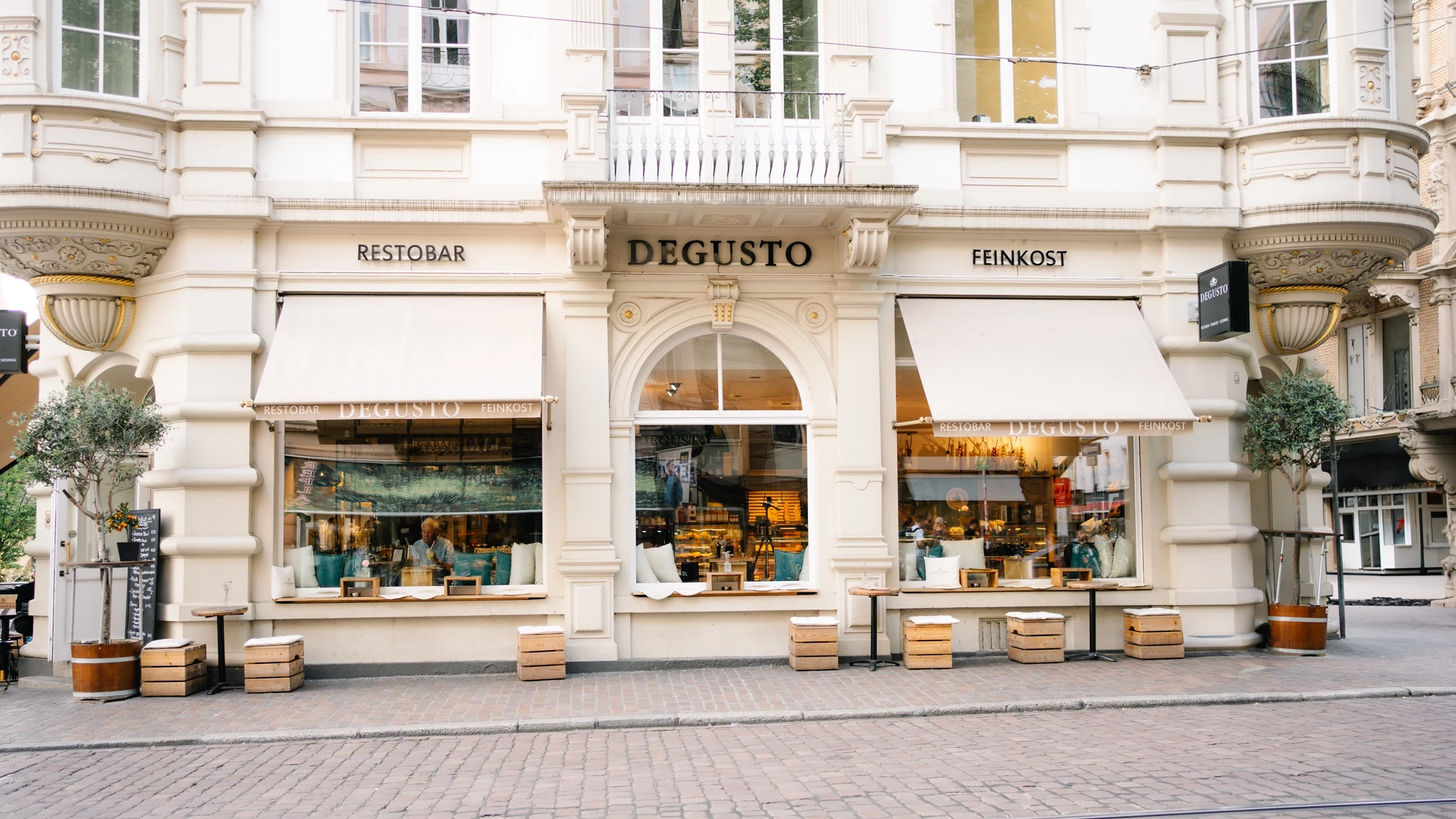 Die Fassade von DEGUSTO in Freiburg mit den Schriftzügen Restobar und Feinkost