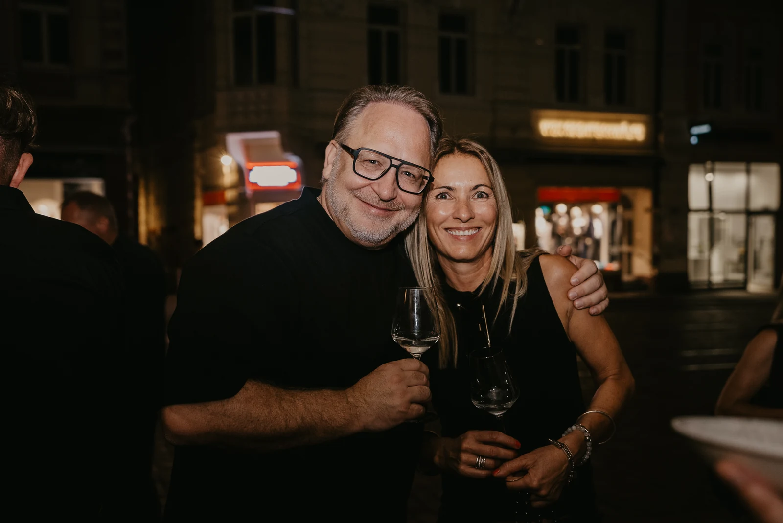 Peter Ganghof und Manuela Klein vor dem DEGUSTO an einem Sommerabend, jeder mit einem Glas Wein in der Hand