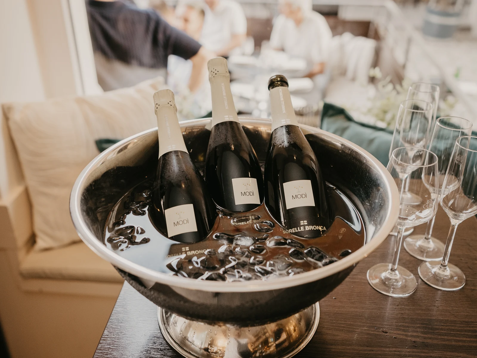 Drei Flaschen Schaumwein im Eiskübel, daneben Gläser