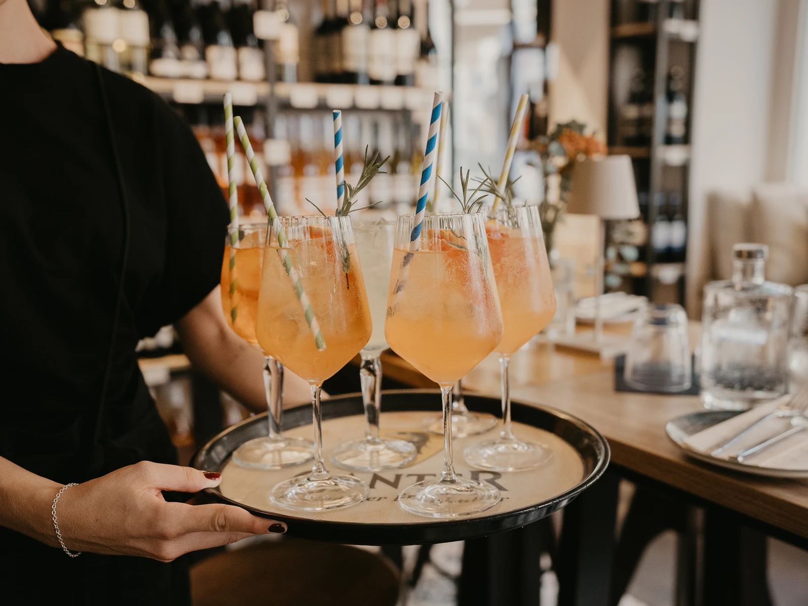 Ein Tablett mit Spritz-Gläsern wird durch den Gastraum getragen