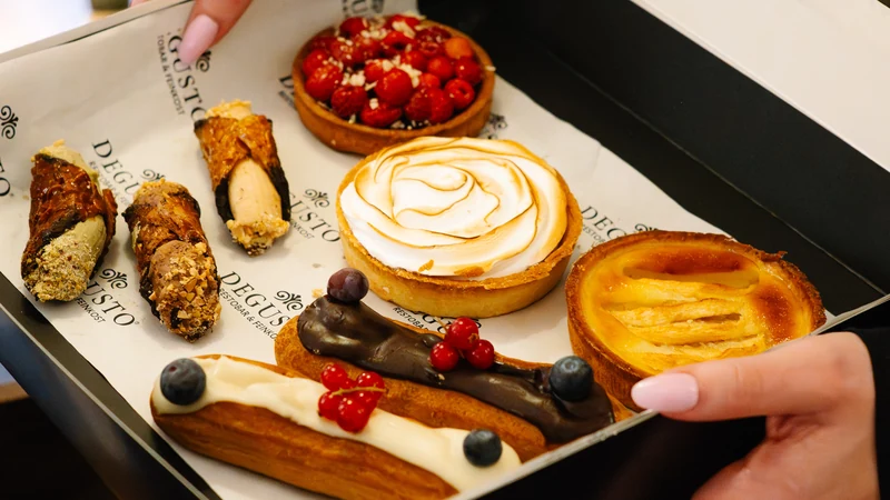 Geöffnete DEGUSTO-Box mit Cannoli, Éclair, Tartelette, Pastel de Nata und Zitronentarte