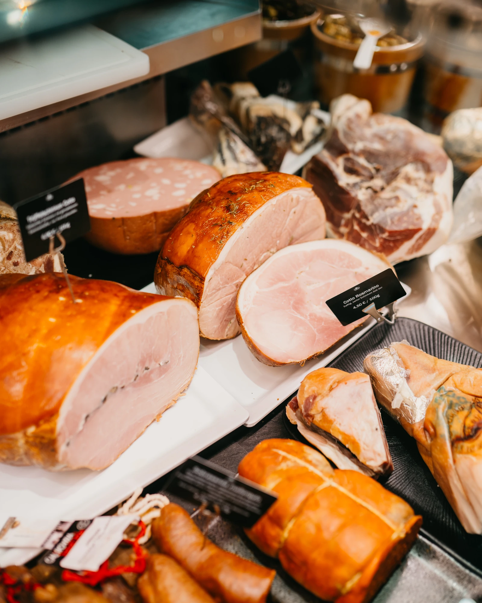 Die Feinkosttheke von DEGUSTO mit angeschnittenem Kochschinken, Rohschinken, Salami und Würsten